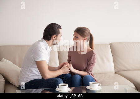 Gut aussehender Mann Hand in Hand der schönen Frau sitzt drinnen, p Stockfoto