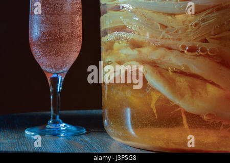 Nahaufnahme von ein Glas, gefüllt mit Scoby Kulturen eine neue Charge und ein Sektglas gefüllt mit dem Endprodukt sprudelnde startbereit. Stockfoto