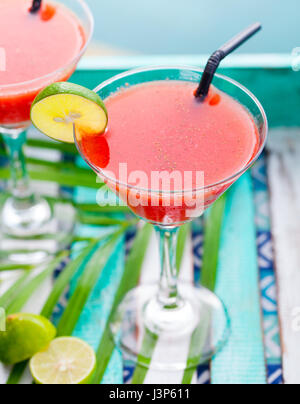 Erdbeer Margarita cocktail auf bunten hölzernen Hintergrund mit Palmzweig. Stockfoto