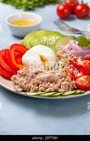 Buddha-Schüssel mit Thunfisch, frischem Gemüse, Quinoa auf konkrete blauem Hintergrund Stockfoto