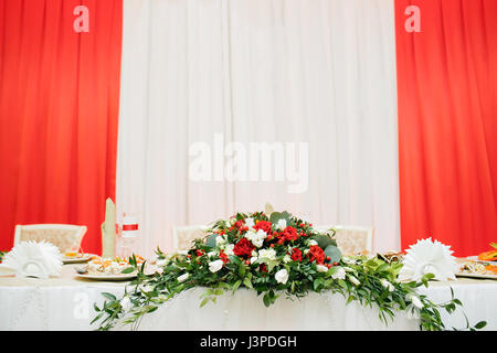 Hochzeitsblumen von weißen und roten Rosen auf Tisch des Brautpaares. Stockfoto