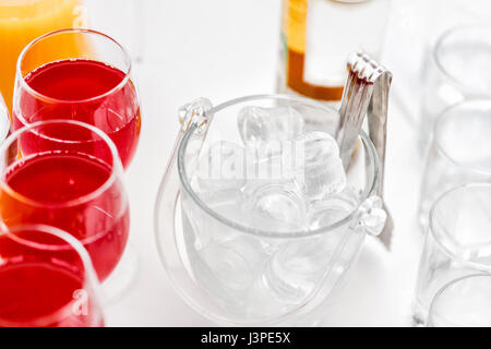 Restaurant-Stehtische in der Cocktail-Party. Eis in einer durchsichtigen Glasschüssel und Metall kleben. festliches Buffet, alkoholische und Alkohol freie Getränke. Stockfoto