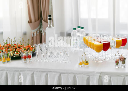 Restaurant-Stehtische in der Cocktail-Party. Eis in einer durchsichtigen Glasschüssel und Metall kleben. festliches Buffet, alkoholische und Alkohol freie Getränke. Stockfoto