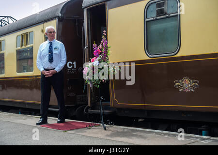 Pullman-Manager, die Passagiere an Bord eines Zuges von Whitby am Pickering auf der North Yorkshire Moors Railway April 2017 begrüßen Stockfoto