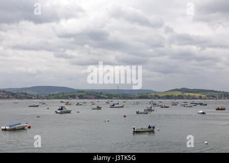 Ein Mann sitzt im Bug des Bootes vor Anker mit hundert anderen in der Mündung des Flusses Exe bei Exmouth Stockfoto