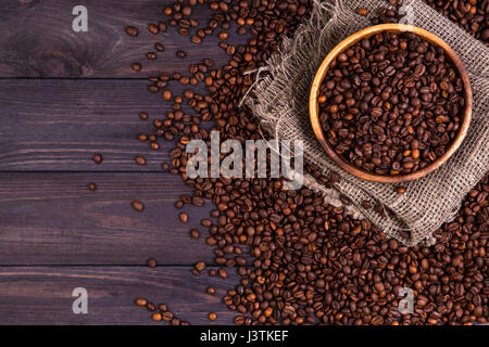 Geröstete Kaffeebohnen in Schüssel auf dunklem Holz Stockfoto