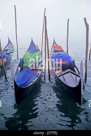 Venedig einen Blick über die Lagune im Morgennebel, Gondeln auf ihren Liegeplatz Masten mit Vordergrund Fokus Stockfoto