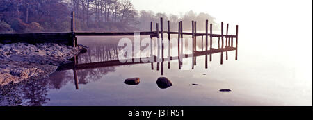 Eine Ponton spiegelt sich in nebligen Morgen des ruhigen friedlichen Derewent Wasser im Lake District Stockfoto