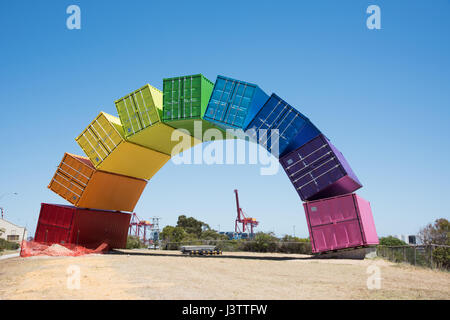 Gewölbte Regenbogen Meer Container Skulptur von Marcus Canning mit Hafenkräne in der Ferne in Fremantle, Western Australia. Stockfoto
