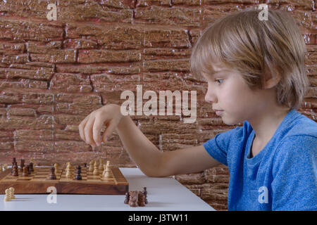 Wenig kaukasischen Junge spielt Schach und so weiter bewegen. Spiel, Bildung, Lifestyle Konzept Stockfoto