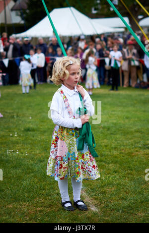 Eine junge, blonde Mädchen steht eine Mai hält pole-Band vor dem Tanzen am Maifeiertag. Stockfoto