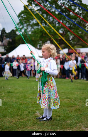 Eine junge, blonde Mädchen steht eine Mai hält pole-Band vor dem Tanzen am Maifeiertag. Stockfoto