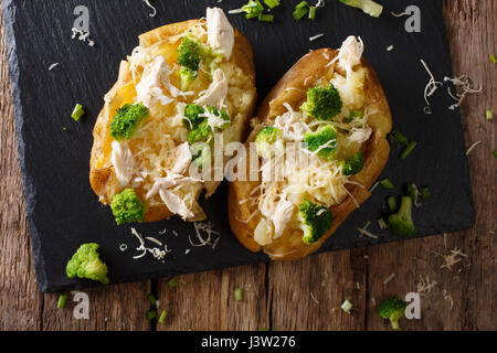 Hausgemachte gebackene Kartoffel mit Käse, Brokkoli und Huhn Closeup auf dem Tisch. Horizontale Ansicht von oben Stockfoto