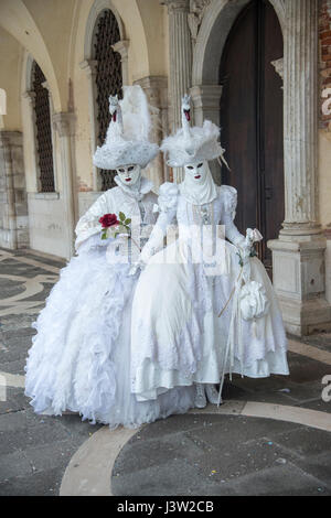 Bild von zwei Individuen in komplementären Schwanenkostümen entlang des Dogenpalastes während des Carnevale Festivals in Venedig, Italien. Stockfoto