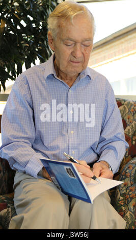 Claude Hodges, ein 99. US-Infanteriedivision-Veteran, diente während der Ardennenoffensive und lebt derzeit bei der Virginia Veteranen Care Center in Roanoke, Virginia, Autogramme eine Kopie der "Schlacht Baby an der Ausbuchtung: The POW Erfahrung von Claude Hodges," von Oberst Greg Eanes. Generalmajor Troy D. Kok, Kommandierender general der US Army Reserve 99. regionale Unterstützung Befehl, besucht Hodges und andere Veteranen in der Mitte April 28. Stockfoto