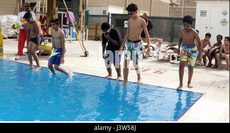 Boy springen Scouts Truppe 965 Kuwait Füße zuerst in den Pool um ihre schwimmen Verdienst Test April 28, Camp Arifjan, Kuwait zu starten. Bereich Support Group-Kuwait Host Nation Angelegenheiten Gastgeber dieser Veranstaltung, die 23 Truppen Verdienstabzeichen in Schwimmen und Fahrzeugsicherheit zu verdienen gab. Stockfoto