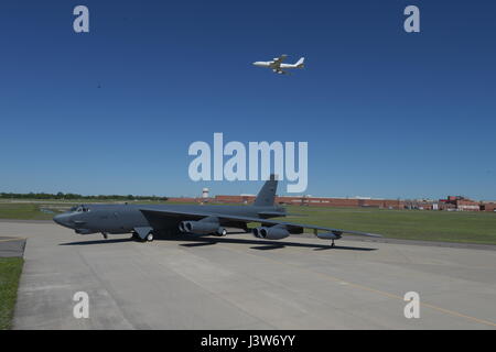 Boeing B - 52H, zwar 60-0005, Posen vor Oklahoma City Air Logistik komplexer Gbd. 3001 nach Generalüberholung einen Boeing E-6 b TACAMO Flugzeuge fliegen Overhead auf 1. Mai 2017, Tinker Air Force Base in Oklahoma. OC-ALC ist verantwortlich für Wartung Depot der beiden Flugzeugflotten mit einem Grossteil der Arbeit statt in dem Gebäude hinter gezeigt. (U.S. Air Force Photo/Greg L. Davis) Stockfoto