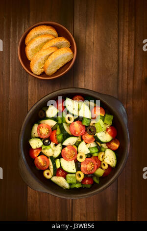 Der schwarze und grüne Oliven, Cherry-Tomaten, grüne Paprika und Gurken, frischer Salat, gewürzt mit Salz, Pfeffer, getrockneter Oregano und Basilikum Stockfoto