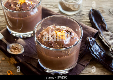 Schokoladenmousse garniert mit Orange Zest in Gläsern über hölzerne Hintergrund schließen sich - köstliche hausgemachte Schokoladenpudding Stockfoto