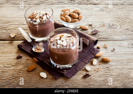 Gesunde Raw vegane Mousse au Chocolat garniert mit Mandeln in Gläsern über hölzerne Hintergrund schließen sich - köstliche hausgemachte Raw Vegan Schokoladenpudding mit Stockfoto