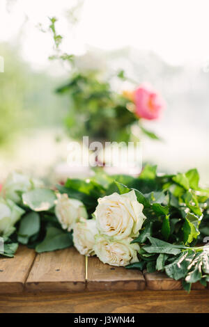 Reisen Blumen und Blumenschmuck Konzept - close-up auf schöne weiße frische Rosen auf Holztisch, Tiefenschärfe, Pfingstrose Blumenstrauß auf Hintergrund. Stockfoto