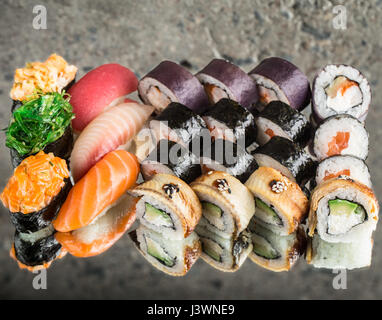 Sushi Set von vier verschiedenen Rollen, Nirigi und Gunkan auf konkrete Hintergrund Stockfoto