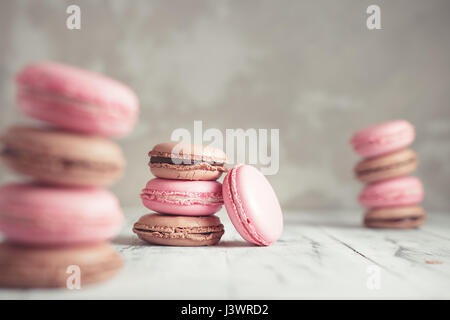 Stapel von Himbeere und Schokolade Pastel farbige Macarons oder Makronen über konkrete Stein Hintergrund Stockfoto