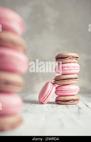 Stapel von Himbeere und Schokolade Pastel farbige Macarons oder Makronen über konkrete Stein Hintergrund Stockfoto