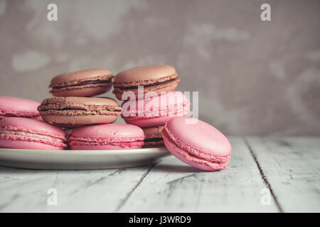 Stapel von Himbeere und Schokolade Pastel farbige Macarons oder Makronen über konkrete Stein Hintergrund Stockfoto