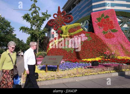 Peking, China. 7. Mai 2017. Ausländer gehen vorbei an Blumendekorationen setzen auf die kommende grüßen Gürtel und Road-Forum für internationale Zusammenarbeit an einer Kreuzung in der Nähe von Xidan Geschäftsviertel im Zentrum von Peking, die Hauptstadt von China, 7. Mai 2017. Beijing wird der Gürtel und Road-Forum für internationale Zusammenarbeit am 14.-15. Mai veranstaltet. Bildnachweis: Chen Xiaogen/Xinhua/Alamy Live-Nachrichten Stockfoto