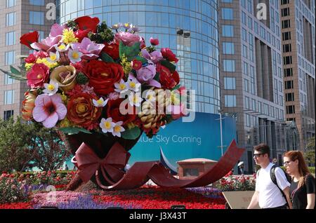 Peking, China. 7. Mai 2017. Ausländer gehen vorbei an Blumendekorationen setzen auf die kommende Gürtel und Road-Forum für internationale Zusammenarbeit an einer Kreuzung in der Nähe von Dongdan Gegend im Zentrum von Peking, die Hauptstadt von China, 7. Mai 2017 zu begrüßen. Beijing wird der Gürtel und Road-Forum für internationale Zusammenarbeit am 14.-15. Mai veranstaltet. Bildnachweis: Chen Xiaogen/Xinhua/Alamy Live-Nachrichten Stockfoto