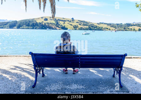 Akaroa, New Zealand - 28. Januar 2017 - sitzt ein weiblicher Touristen auf einer Bank am 28. Januar 2017 in Akaroa, Neuseeland. | weltweite Nutzung Stockfoto