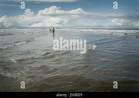 Schwimmer waten weit draußen in der sanft abfallenden Strand. Stockfoto