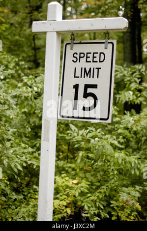 Ein "Speed Limit 15" Schild an einem Staatspark Straße, tropft im Regen mit dem Hintergrund der Blätter im Caumsett State Park in Lloyd Harbor, New York. Stockfoto