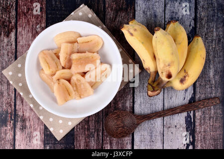 Thai beliebtes Dessert, fertig gekochte Banane in Sirup serviert und Löcher Banane serviert auf Holz. Stockfoto
