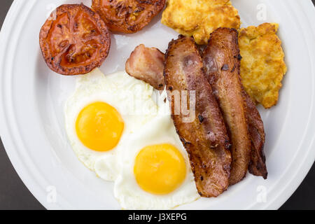 Frühstück mit Spiegeleiern, Speck, Tomaten und Kartoffeln Pfanne Kuchen hautnah Stockfoto