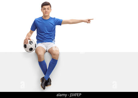 Teenager-Football-Spieler sitzen auf einem Panel und zeigen recht isoliert auf weißem Hintergrund Stockfoto