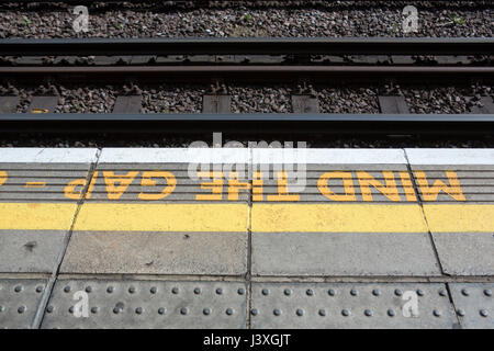 Rand des einen Bahnsteig mit der Meldung beachten, dass die Lücke auf den Stein gemalt gefliesten Boden. Stockfoto