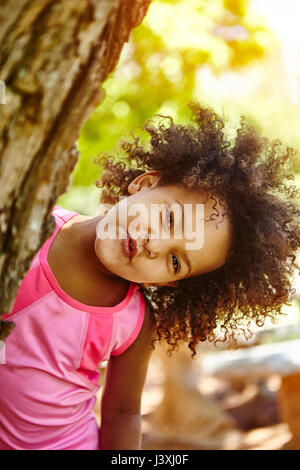 Porträt eines jungen Mädchens, Peering hinter Baum, lächelnd Stockfoto