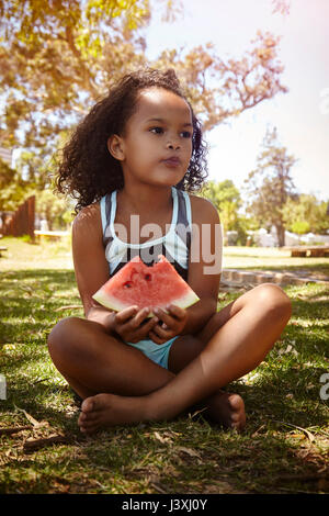 Porträt der jungen Mädchen, sitzend auf Gras, Essen, Wassermelone Stockfoto