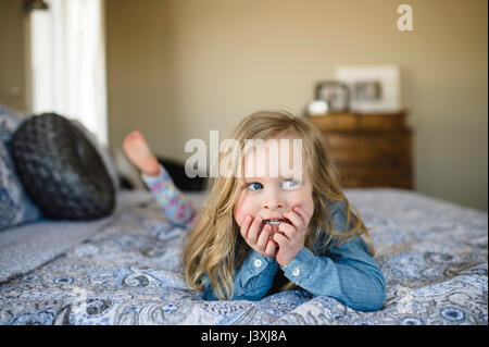 Mädchen auf Bett Blick seitlich liegend Stockfoto