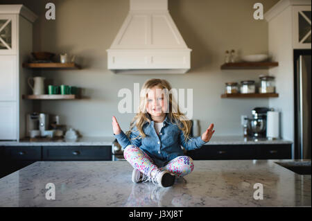 Portrait von Mädchen sitzen im Schneidersitz auf den Küchentisch Stockfoto