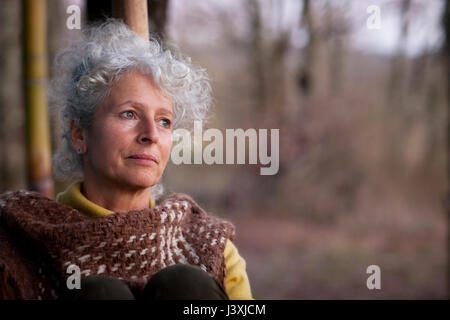 Portrait von grauen Haaren reife Frau anstarrt, im Wald in der Dämmerung Stockfoto