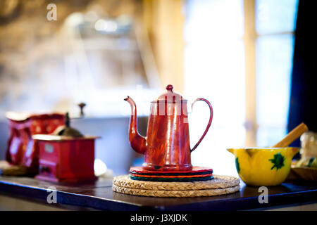 Traditionelle rote Kaffeekanne und Kaffeemühle auf den Küchentisch Stockfoto