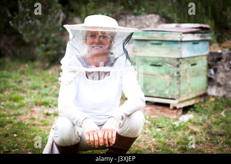 Porträt von weiblichen Imker hocken im Garten Stockfoto