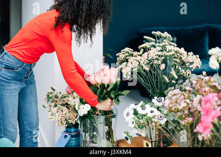 Weibliche florist Anordnen von Rosen in Vase für Shop Anzeige Stockfoto