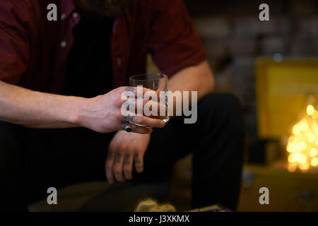 Den mittleren Abschnitt der Mann mit dem tätowierten Finger holding Zuhaltung des Geistes in Public House Stockfoto
