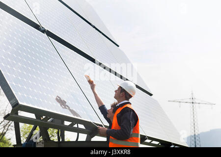 Männliche und weibliche Ingenieure mit Multimeter auf Solarzellen Stockfoto