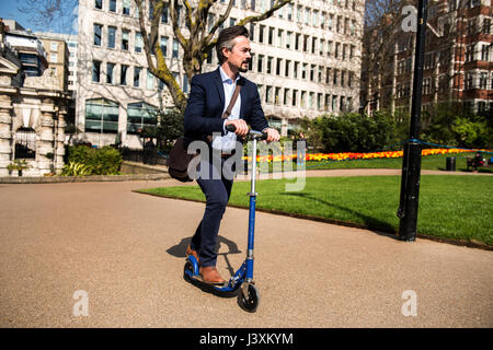 Geschäftsmann auf Roller, London, UK Stockfoto