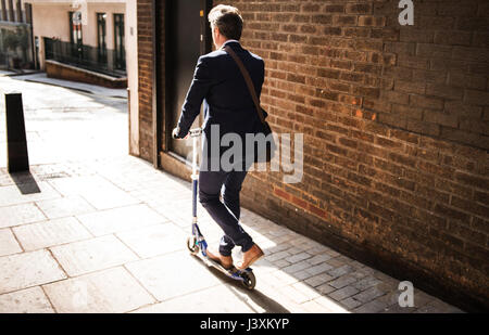 Geschäftsmann auf Roller, London, UK Stockfoto